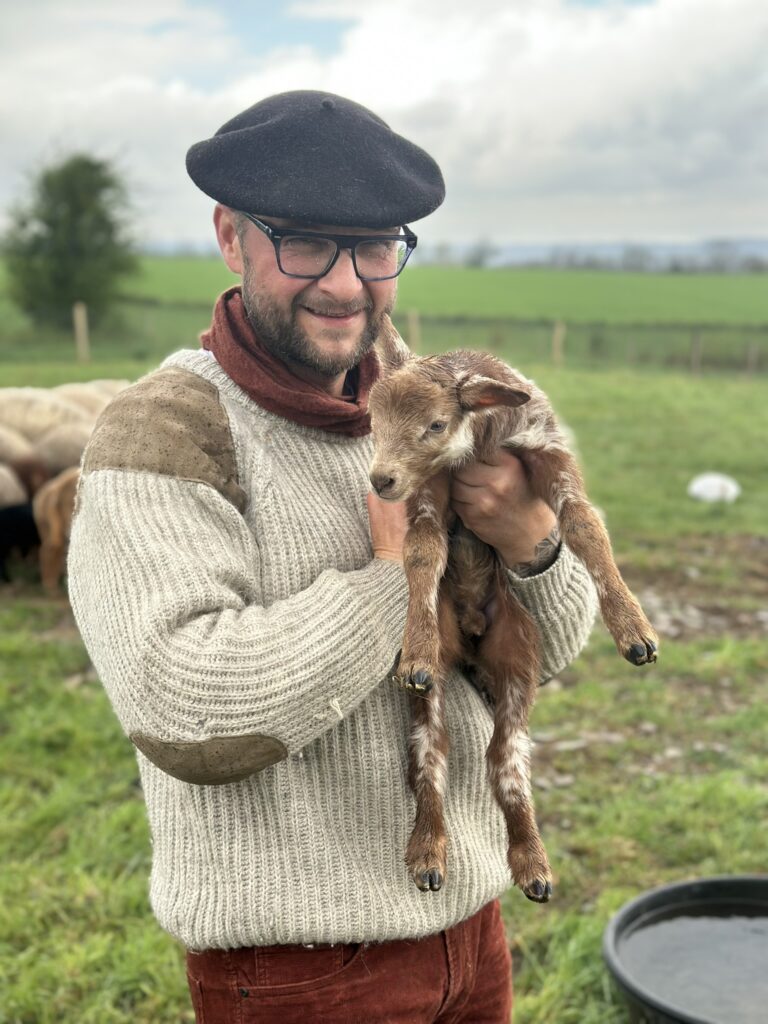 Lionel Huber, gardien du Domaine de Hurlevent, portant un chevreau à la ferme à Aywaille, Wallonie